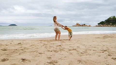 Mother spinning kid on beach. Stock Footage 273282843