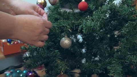 A mother started decorating the Christmas tree, hanging a pink Christmas ball Stock Footage 166534240