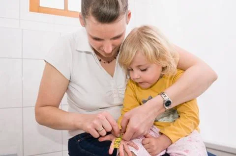 Mother sticking bandage on daughter hand Stock Photos