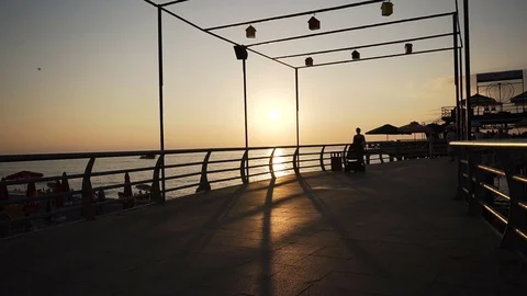 Mother with a stroller cot goes along the evening embankment near the sea 스톡 동영상 78535772