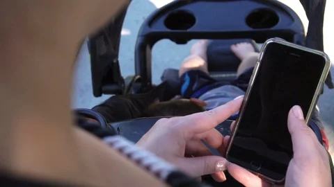 Mother with stroller on sidewalk looking through her phone Stock Footage 129384435