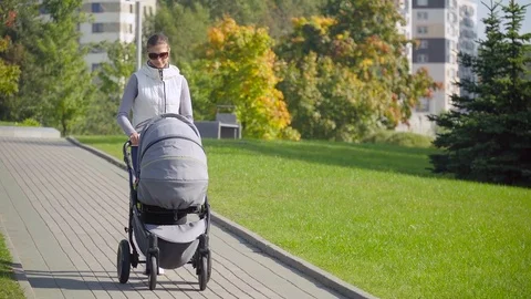 Mother with a stroller walking in the Park Stock Footage 81367466
