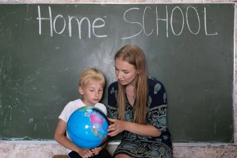 Mother is studying a world map on a globe with her son. Stock Photos