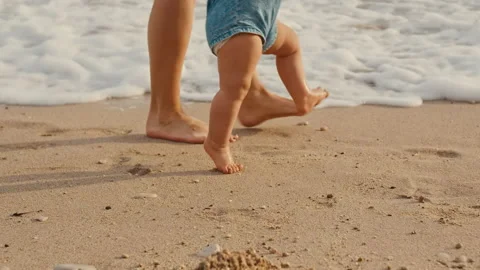 Mother is support her child to do the first steps on beach sand Stock Footage 196744910