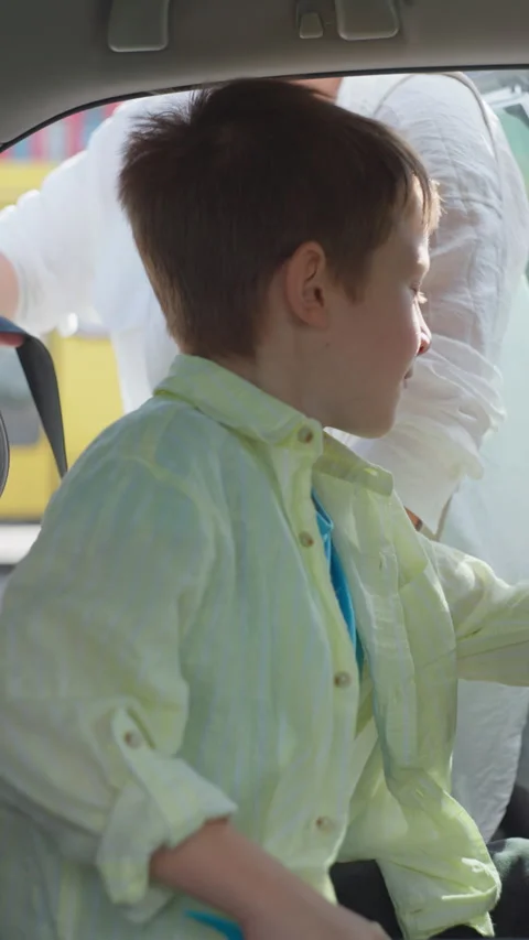 Mother Supporting Her Son as He Sits in a Child Car Seat Preparing for Drive Stock Footage 288633728