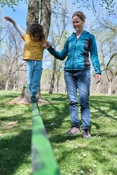 Mother supporting son doing slacklining in park Stock Photos
