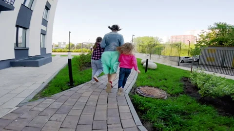 Mother is taking her two young daughters for a walk in a park. They are enjoying Stock Footage 283677128