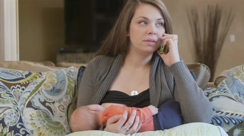 Mother talking on the phone while breastfeeding Vídeo Stock 54136384