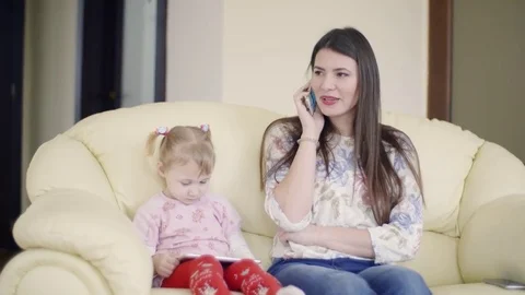 Mother is talking on phone while daughter is wathing something on the tablet. 스톡 동영상 79713573