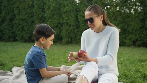 Mother talking to son while holding apples in green backyard Stock-Footage 119991855