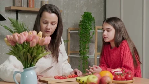 Mother talks to her daughter while she prepares the vegetable salad. Stock Footage 151914332