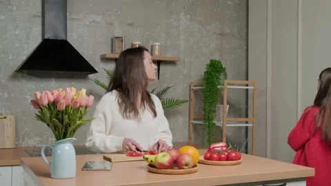 Mother talks to her daughter while she prepares the vegetable salad. Stock Footage 152726892