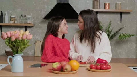 Mother talks to her daughter while she prepares the vegetable salad. Stock Footage 155651137