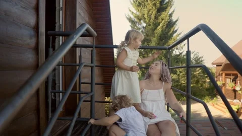 A mother talks to her daughters while sitting on the balcony near the entrance Video stock 283208928