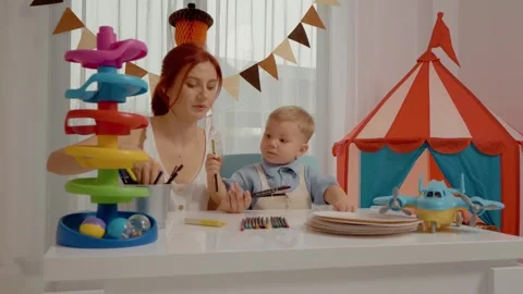 Mother teaches child colors while playing with crayons in cheerful room Stock Footage 329227544