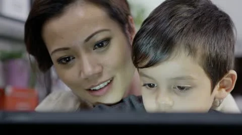 A mother teaches her young son how to use a computer Stock Footage