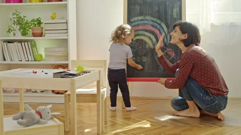 Mother teaching child to write letters on chalkboard at home. Stock Footage 252124482