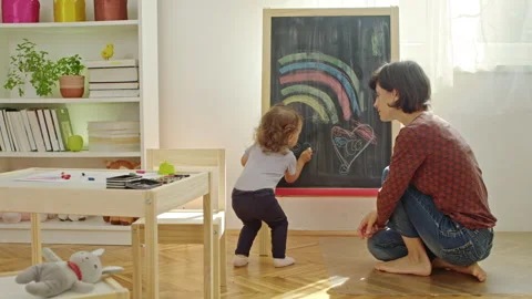 Mother teaching child to write letters on chalkboard at home. Stock Footage 252124674