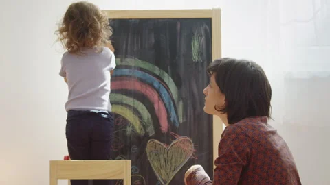 Mother teaching child to write letters on chalkboard at home. Stock Footage 252125175