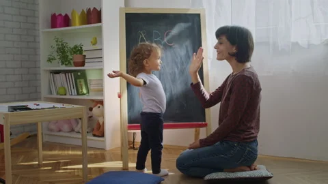 Mother teaching child to write letters on chalkboard at home. Stock Footage 252127436