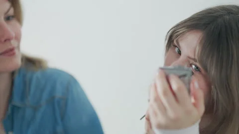 Mother teaching daughter how to apply makeup Stock Footage 332444273