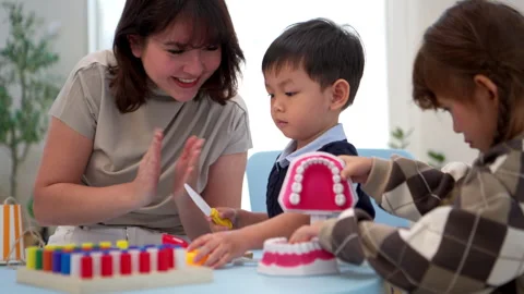 Mother teaching her child about dental care using a tooth model Stock-Footage 339570478
