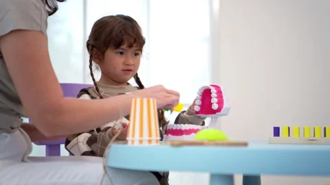Mother teaching her child about dental care using a tooth model Video stock 339570600