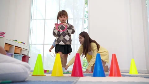 Mother teaching her child how to play a ring toss game properly Stock Footage 339567723