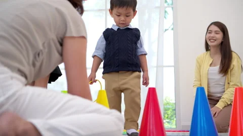 Mother teaching her child how to play a ring toss game properly Stock Footage 339569330