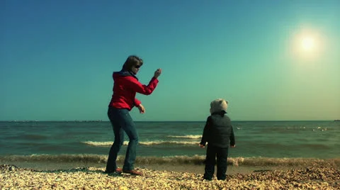 Mother teaching her son to throw sea shells 스톡 동영상 26305157
