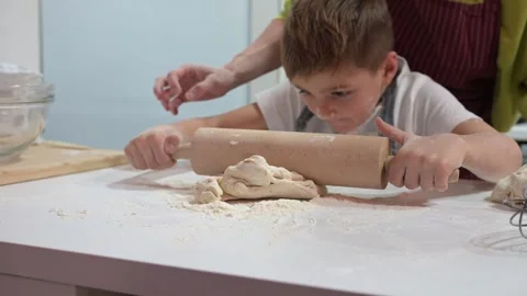 Mother teaching her young son to roll dough in the kitchen 스톡 동영상 324558535