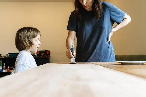 Mother teaching her young son home renovation and painting furniture together Stock Photos