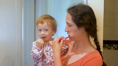 Mother teaching kid teeth brushing. Mother and daughter brushing teeth together Stock Footage 116166433