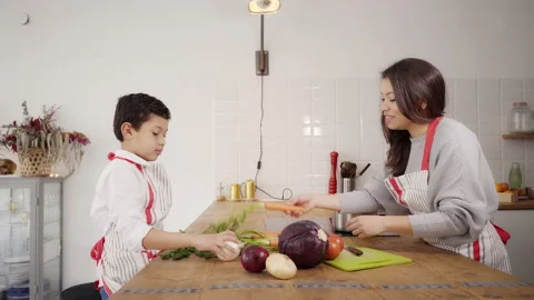 Mother teaching the name of different vegetables to her son in the kitchen. T Video stock 150664526