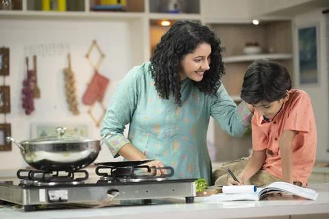 Mother Teaching Son While Cooking In Kitchen Stock Photos