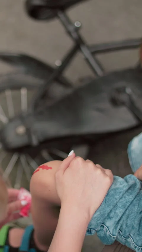 Mother Tends to Sons Bleeding Leg After Bicycle Accident Stock Footage 316960713