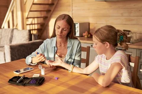 Mother Testing Blood Sugar Level of Daughter with Diabetes at Home Stock Photos