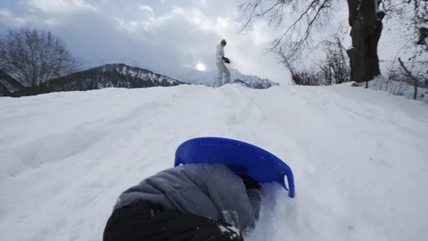 Mother throws snowballs at son hiding behind shield and laughing Stock Footage 121754155