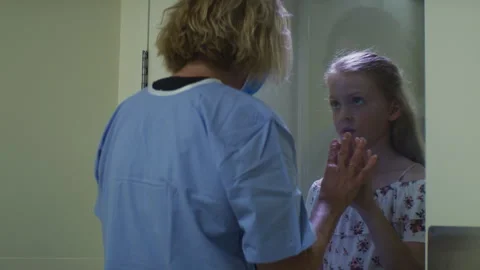 A mother Trying to Touch the Hand of Her Daughter over Glass in the Hospital Stock Footage 264096592