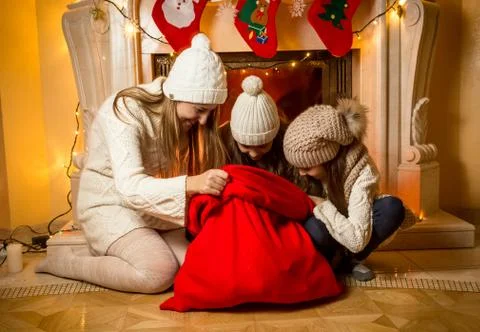 Mother with two daughters looking inside of Santa's red bag Stock Photos