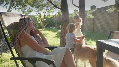 A mother with two daughters, a rabbit and a dog are in the garden on a sunny day Stock Footage 284304854