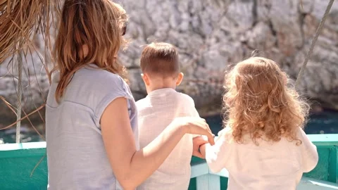 Mother with two small children stands on board ship. They look at mountain they Stock Footage 282192386
