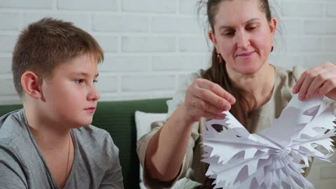 Mother unfolding paper craft while son watches with amazement Stock Footage 306702443