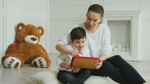 Mother using a digital tablet with her son at home Stock Footage 106309287