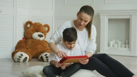 Mother using a digital tablet with her son at home Stock Footage 106309656