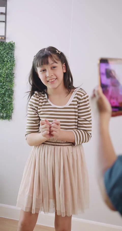 A mother is using her smart phone to take a video while her daughter is dancing Stock Footage 269168258