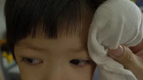 Mother using ice compress treatment on swell head child, slow motion scene Stock Footage 133160534