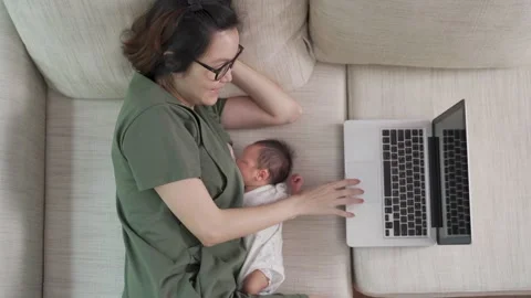 Mother using laptop and breast feeding baby. Stock Footage 157974768