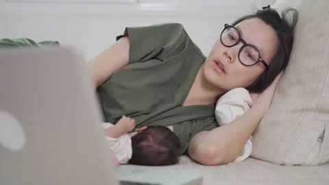Mother using laptop and breast feeding baby. Stock Footage 157974841