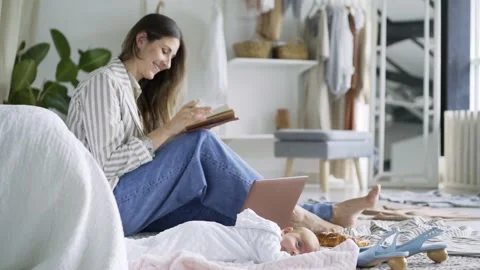 Mother using laptop on carpet by sleeping baby Video stock 149971958